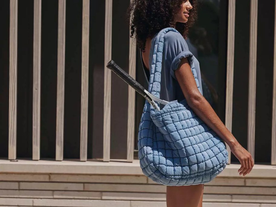 woman standing with a blue free people bag