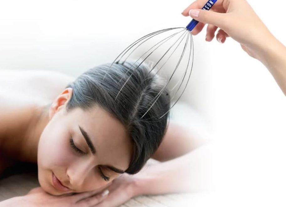 hand holding scalp massager to sleeping womans head