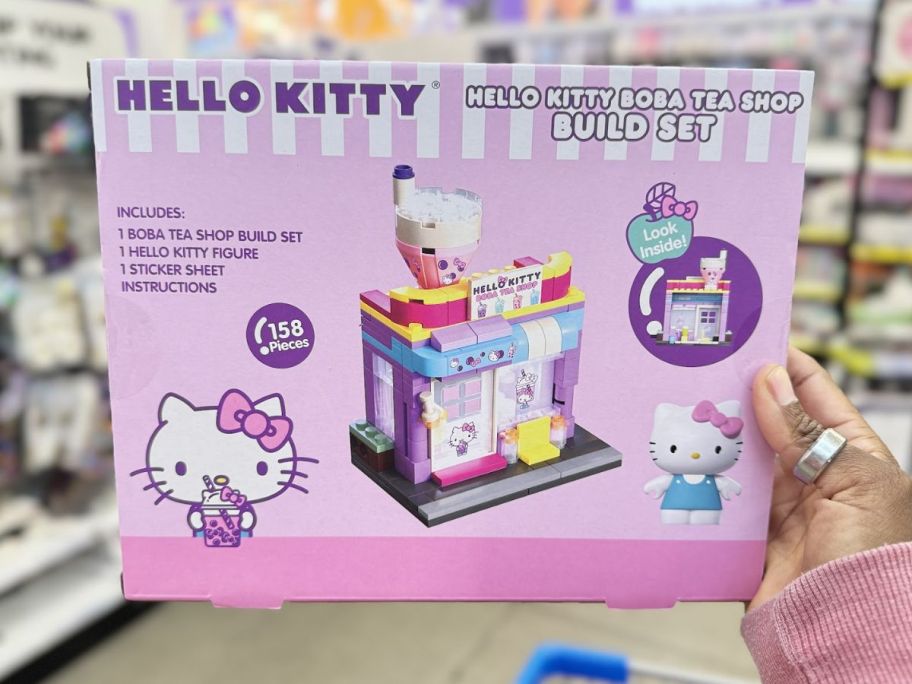 a womans hand holding a hello kitty building block set