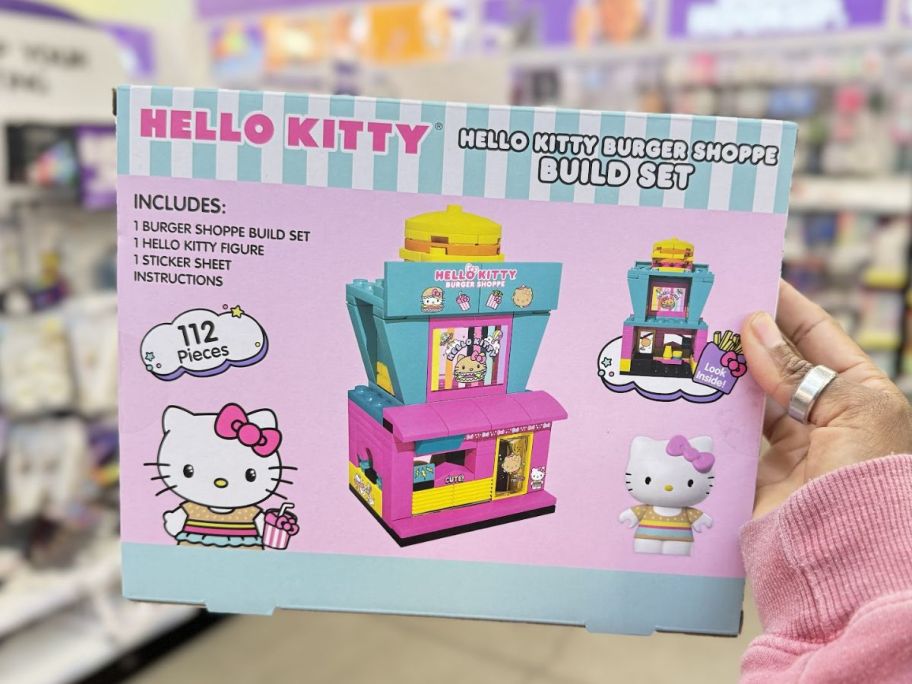 a womans hand holding a hello kitty building block set