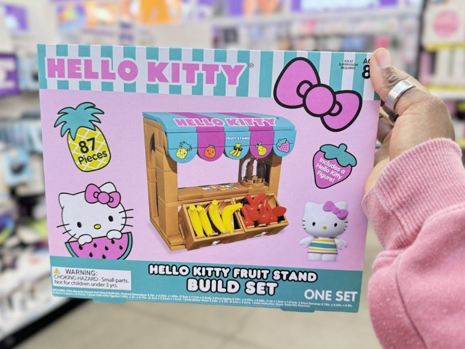 a womans hand holding a hello kitty building block set