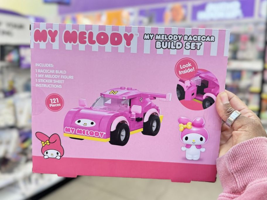 a womans hand holding a hello kitty building block set