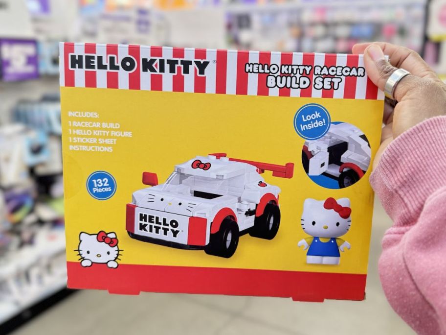 a womans hand holding a hello kitty building block set