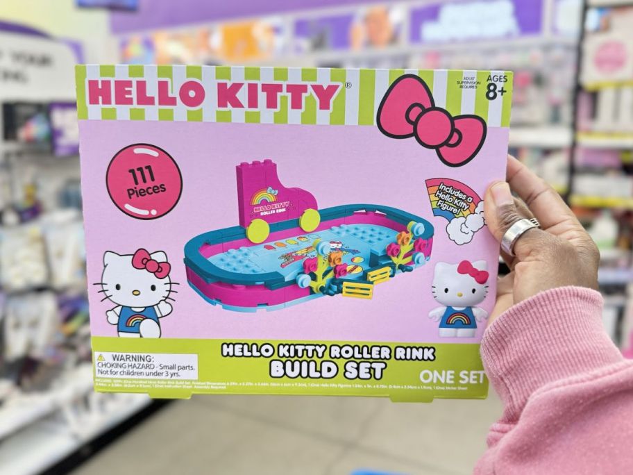 a womans hand holding a hello kitty building block set