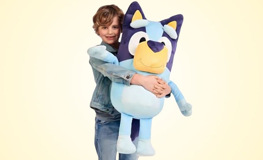 a kid holding a jumbo bluey dog plush