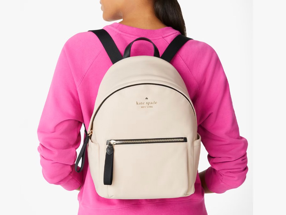 woman wearing white kate spade backpack