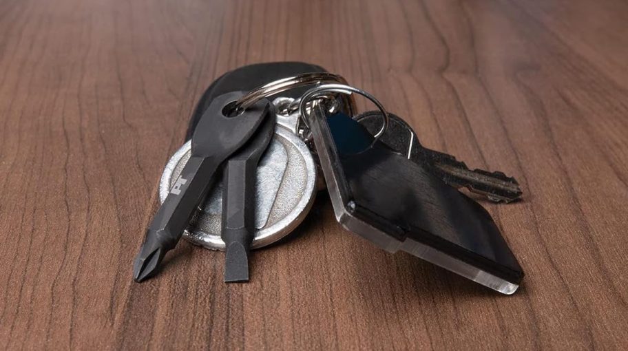 black screwdriver keychain on set of keys laying on wood table