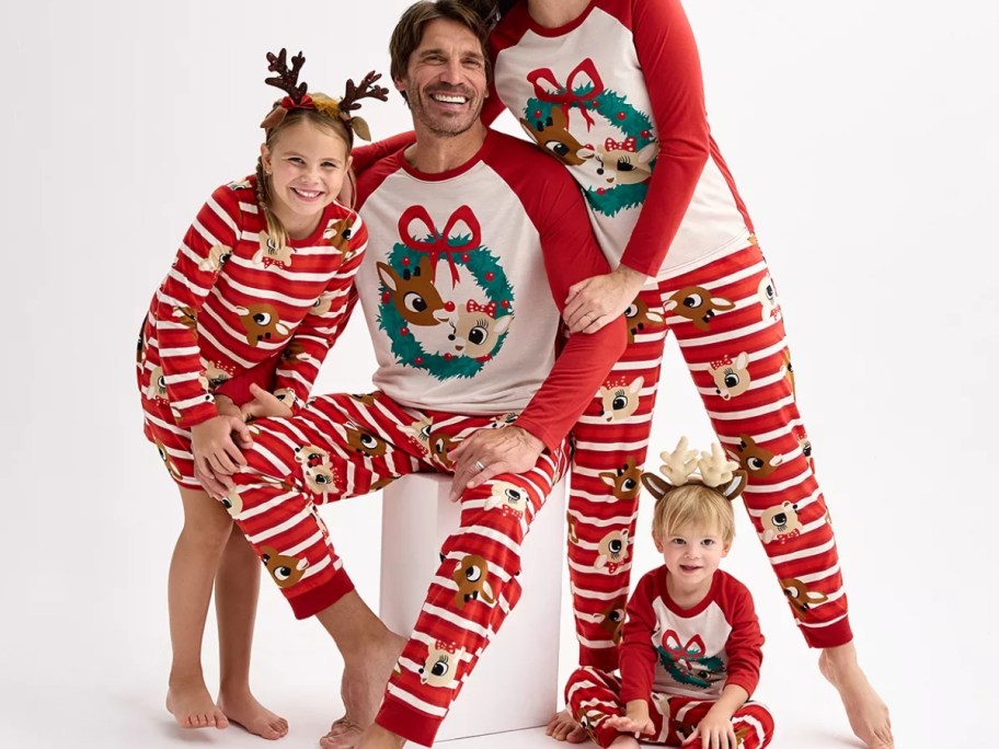 mom, dad, little girl, and toddler boy wearing matching Rudolph the Red Nosed Reindeer pajamas