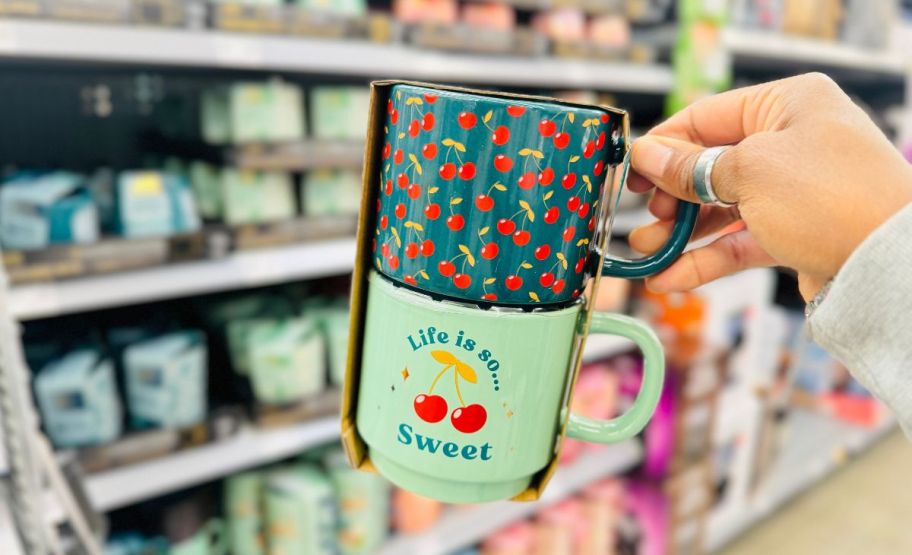 a womans hand holding a 2 pack of stacking mugs