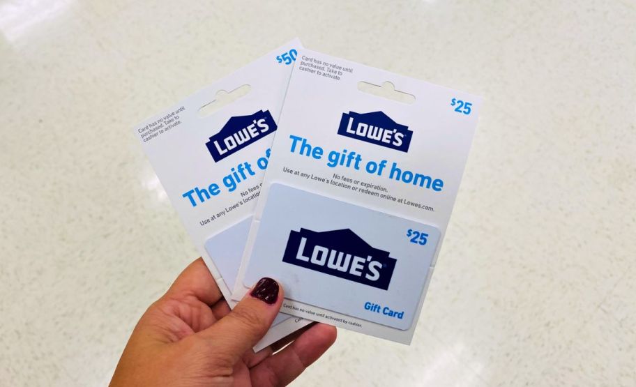 a woman's hand holding two lowes gift cards in a dollar general store