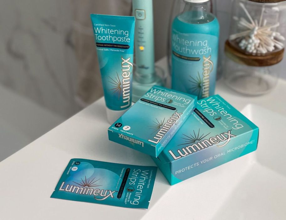 a tube of Lumineux toothpaste shown with whitening strips on a bathroom counter