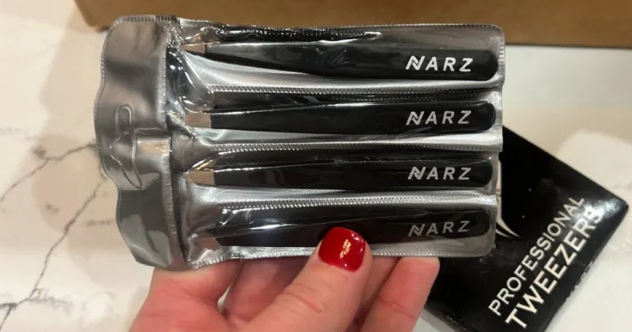 hand holding a four pack of professional tweezers