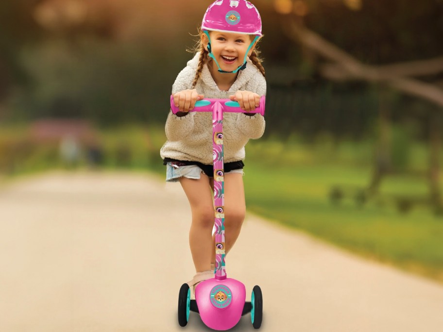 girl riding on pink paw patrol scooter wearing helmet 