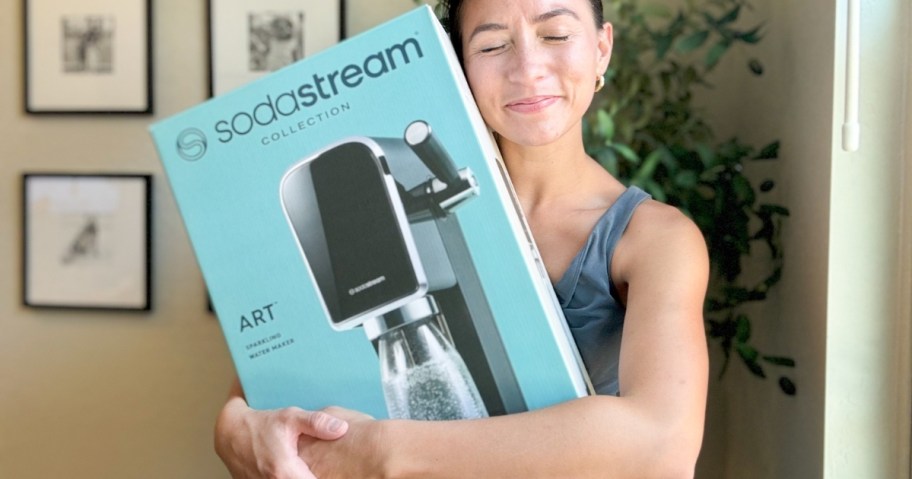 woman hugging a blue box with a SodaStream Art machine in it