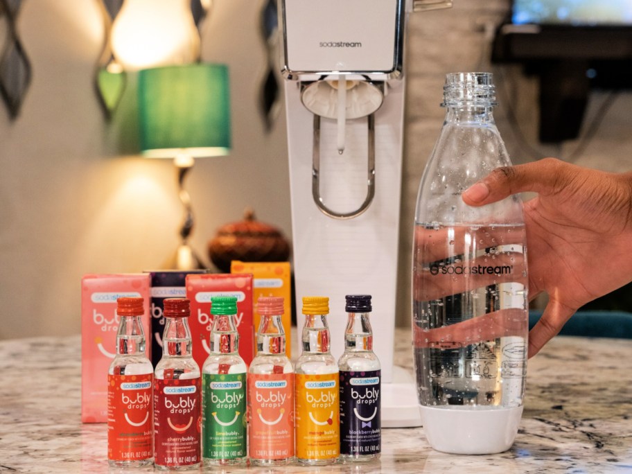 woman holding a bottle in front of a sodastream and bubly flavors