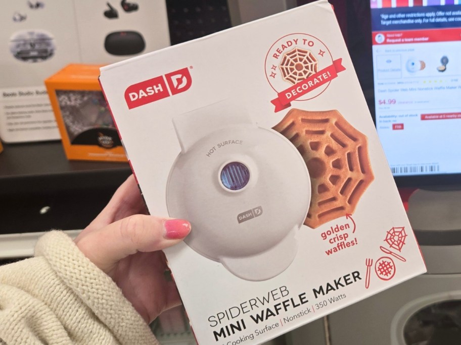 hand holding a box with a spiderweb Dash Mini Waffle Maker in it