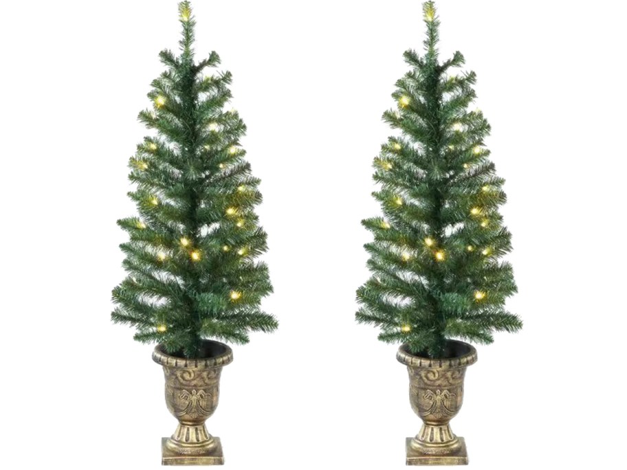 two artificial christmas trees in gold pots 