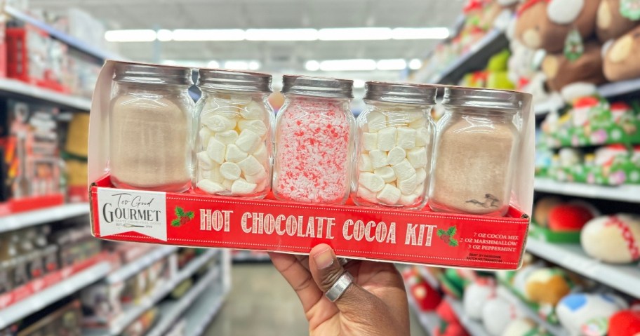 hand holding a box with 5 glass jars with various items to make hot cocoa, the box label says "Hot Chocolate Cocoa Kit"