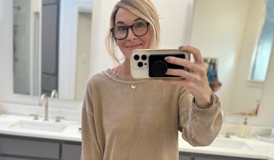 woman holding a phone and wearing a ribbed sweater