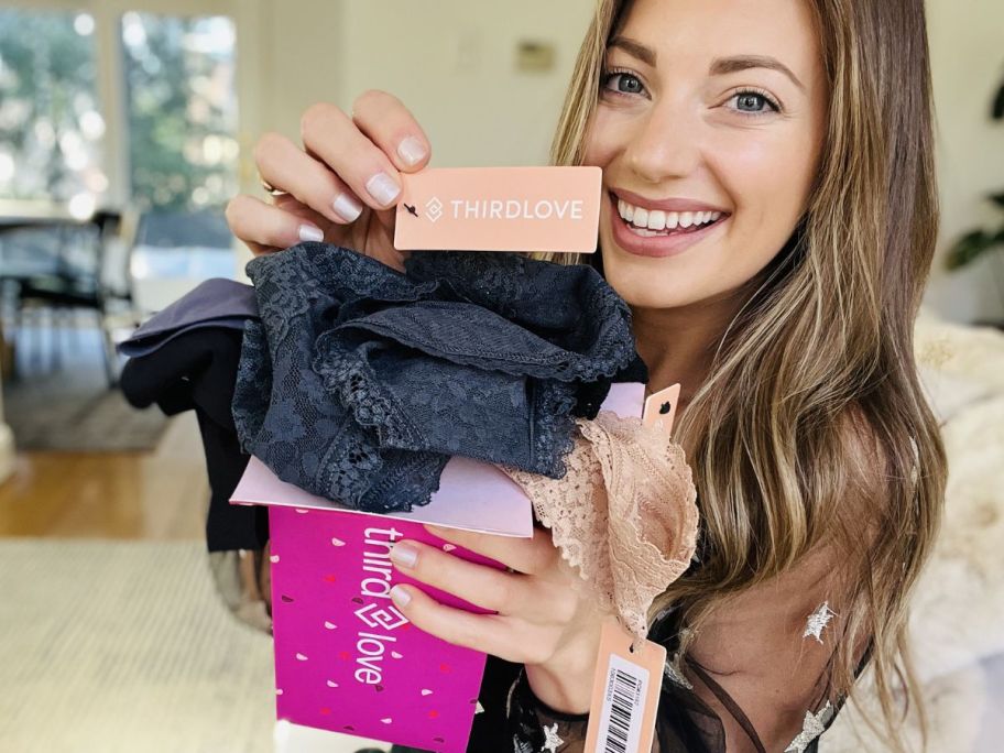 a woman holding the tag attached to a pair of blue underwear. 