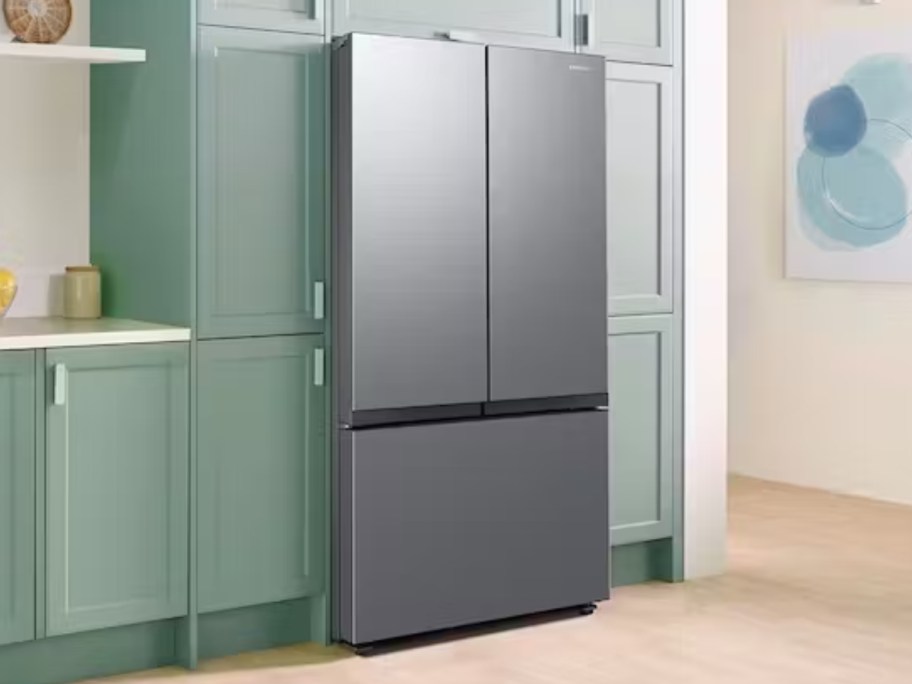 a stainless steel 3 door fridge in a kitchen with green cabinets