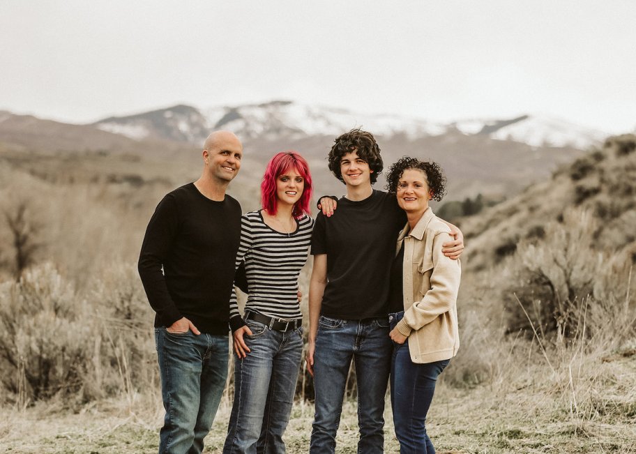 family posing in mountain field smiling