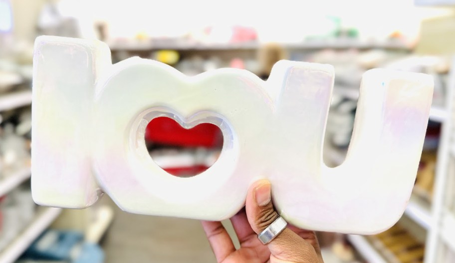 hand holding a white vase that says i love you