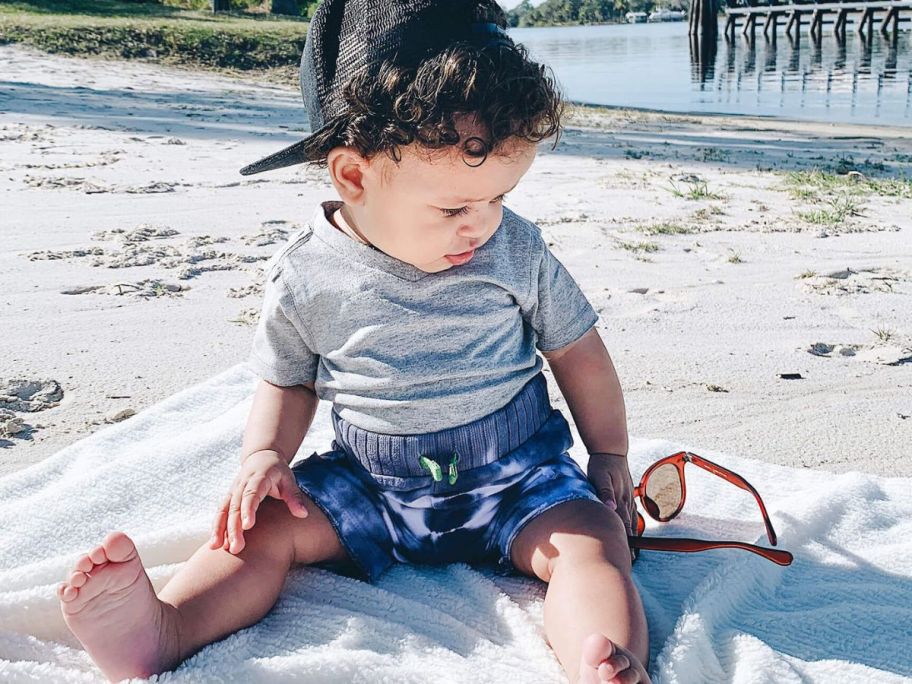 A baby boy wearing a Burt's Bees V-Neck Tee at the beach