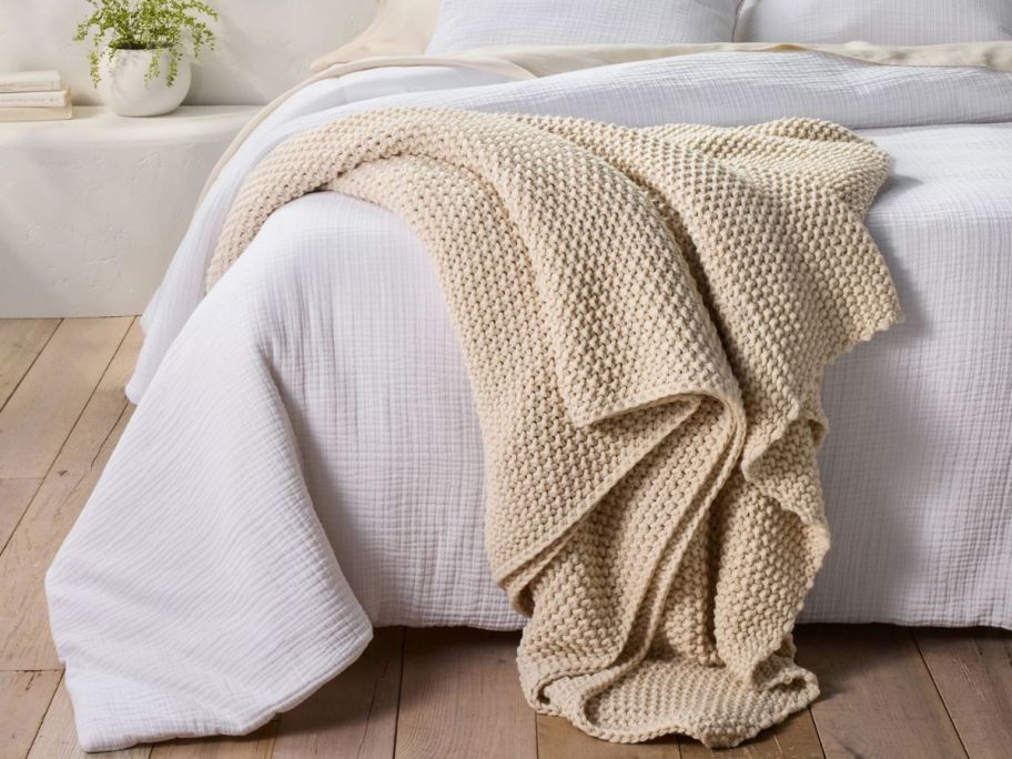 a chunky knit blanket draped across a bed