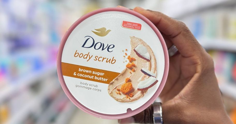 Hand holding a tub of Dove Body Scrub