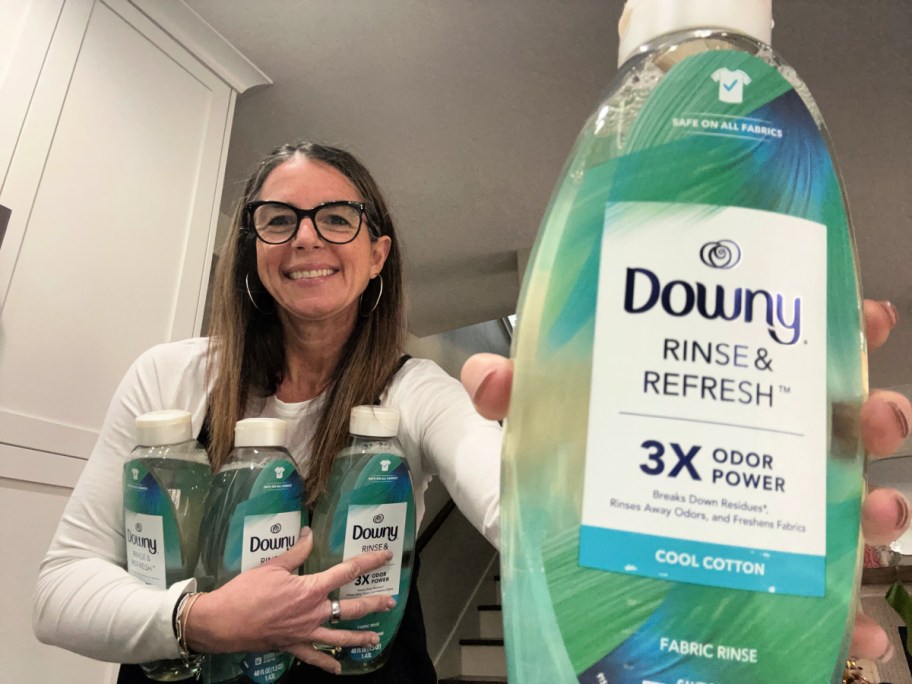 woman holding four bottles of Downy, rinse and refresh