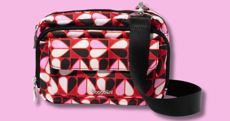 a crossbody bag with red, pink, black, and white hearts and a black strap