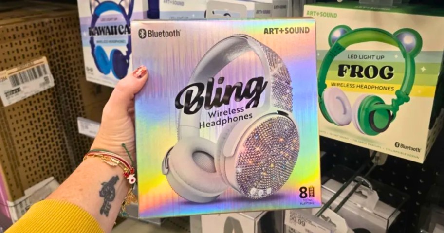 hand holding a shiny box with a pair of kid's sparkly silver headphones