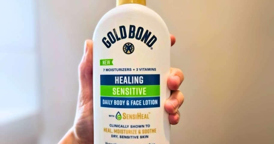 hand holding a white bottle of Gold Bond Healing Sensitive Lotion 