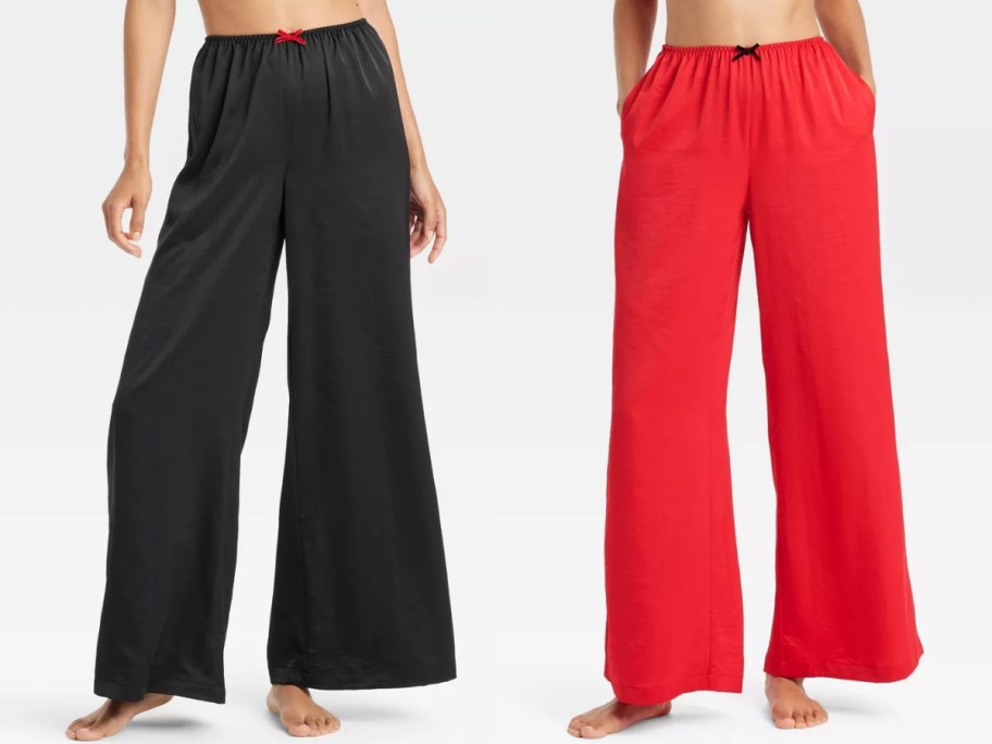 the lower half of 2 women - both are wearing wide leg satin pajama pants, one pair is black, the other is red