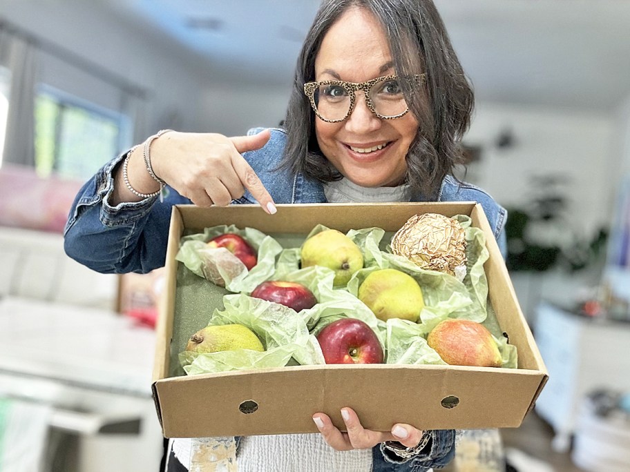 woman holding up and pointing to a Harry & David Pears & Apples Gift Box