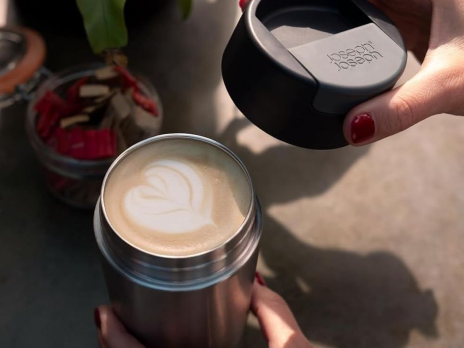 A Joseph Joseph Travel Tumbler filled with a latte with a heart in the top of the foam