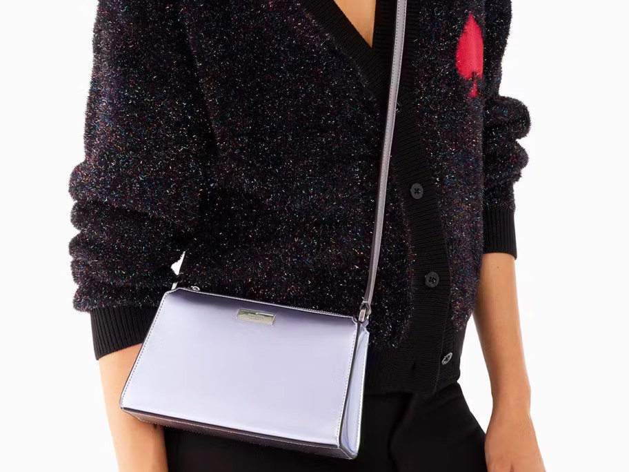 woman in black sweater with metallic blue crossbody bag