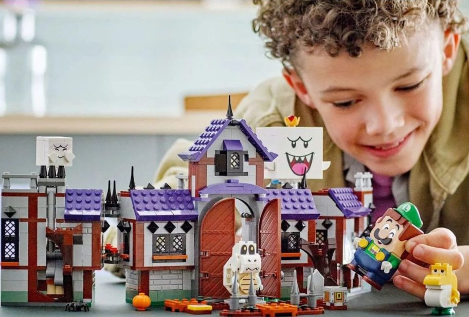 Little boy playing with a LEGO Super Mario King Boo’s Haunted Mansion