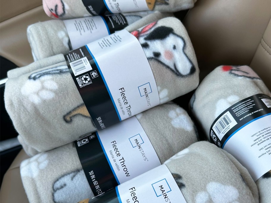 multiple dog print fleece throws in a pile