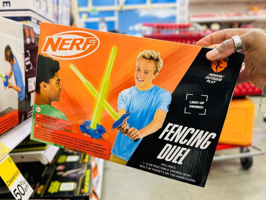 a womans hand holding a nerf fencing set box