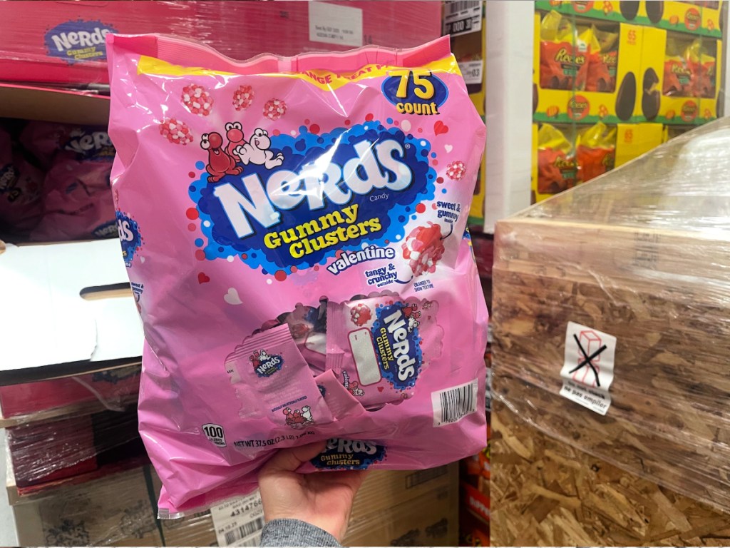 Person holding up pink bag of nerds, gummy clusters, valentine classroom treat bags inside Sam's Club