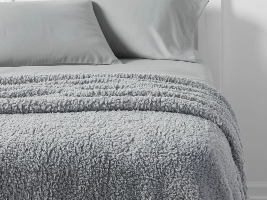 a gray shearling blanket draped across a bed