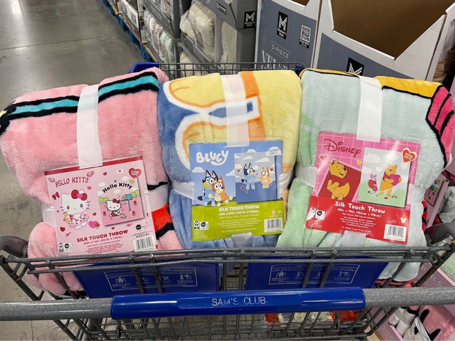 A Sam's Club cart with 3 licensed character valentine's day throw blankets in the front basket