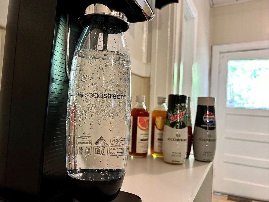 sodastream on counter with sparkling water being made in it