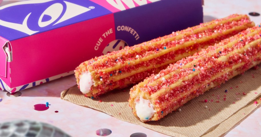 Churros on wooden board with pink confetti sprinkles next to Taco Bell box