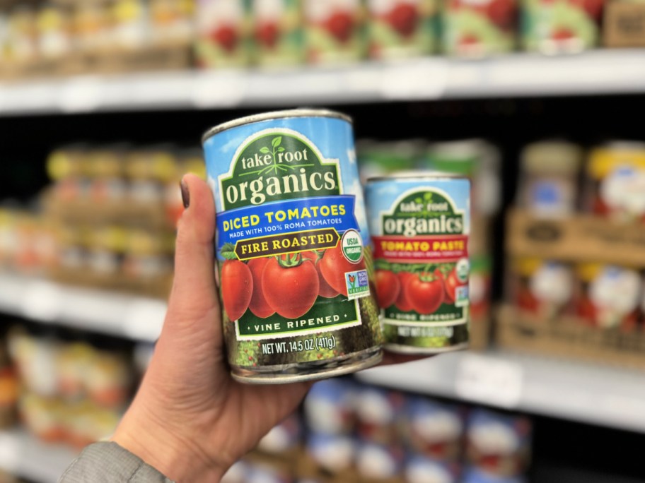 person holding up cans of Take Root Organics at Walmart