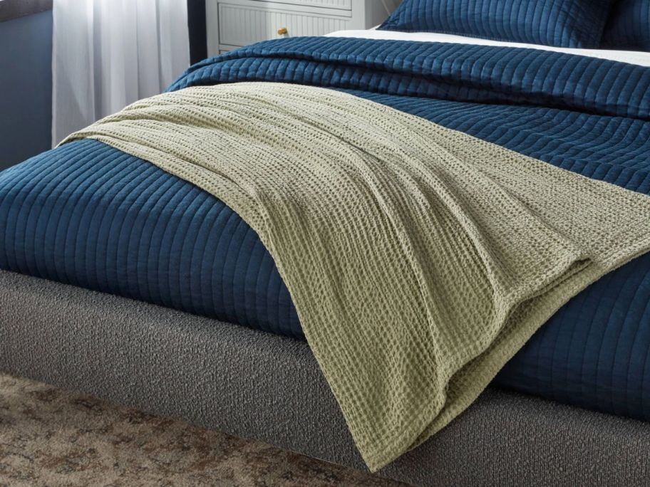 a light green blanket draped across a bed