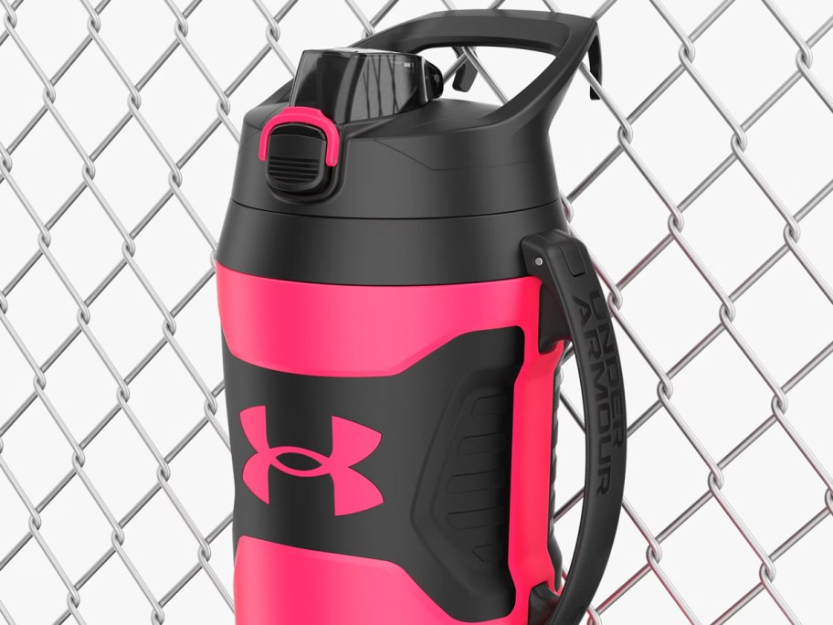 pink and black water jug hanging off chain link fence