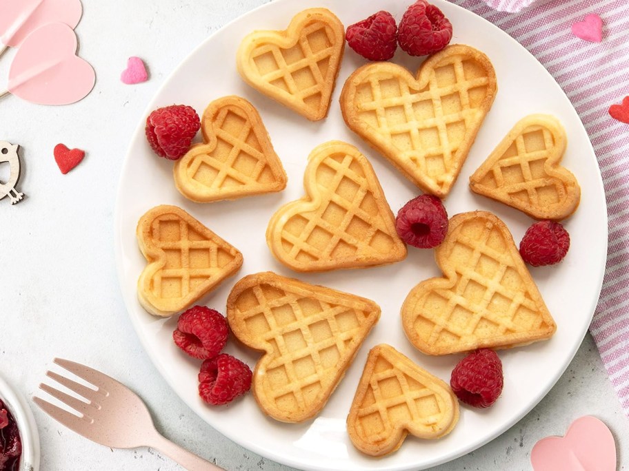 heart shaped mini waffles on a plate with raspberries